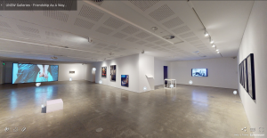 Panoramic view of an art gallery exhibiting various artworks, including large wall projections and framed pieces, with informational icons for a virtual tour.