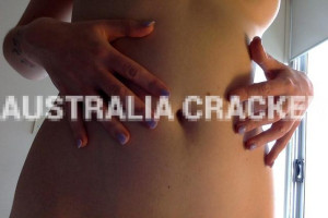 Close-up of a woman's torso with hands resting on her skin, nails painted purple, with a watermark reading 'AUSTRALIA CRACKER' across the photo.