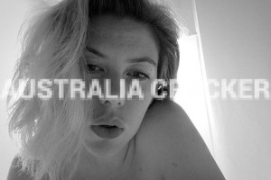 Monochrome close-up of a woman gazing directly at the camera, creating an intimate atmosphere, with 'AUSTRALIA CRACKER' watermarked over the image.