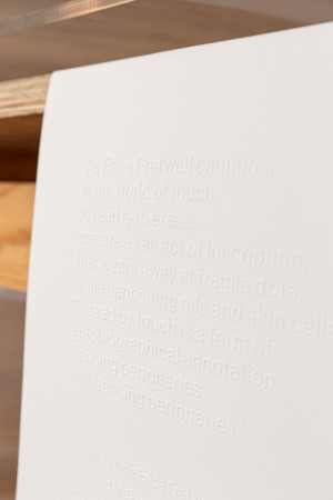 Embossed text on a white page reads As Erica Fretwell cautions, in the world of touch, to read is to erase, erasure as an act of inscription, that wears away at fragile dots, while depositing oils and skin cells. To read by touch is a form of autobiographical annotation, sensing peripheries, self-sensing peripheries.