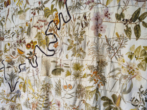 Close-up of a textile art piece featuring botanical illustrations.