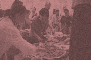 A group of people gathered around food, filling their plates with lunch. 